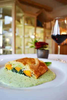 a piece of food on a white plate with a glass of wine at Mineralienhotel Natznerhof in Naz-Sciaves