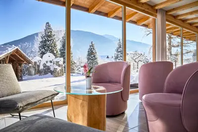 a room with a table and chairs and a snowy mountain at Mineralienhotel Natznerhof in Naz-Sciaves