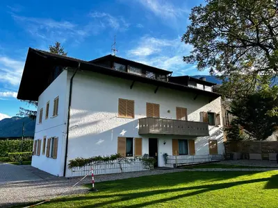 a white house with a black roof and a yard at St. Vigilhof in Nalles