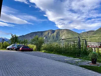 a parking lot with cars parked in front of a mountain at St. Vigilhof in Nalles