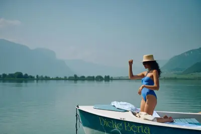 a woman in a bikini sitting on a boat on the water at Leuchtenburg am See in Caldaro