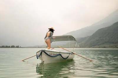a woman is sitting on a boat in the water at Leuchtenburg am See in Caldaro