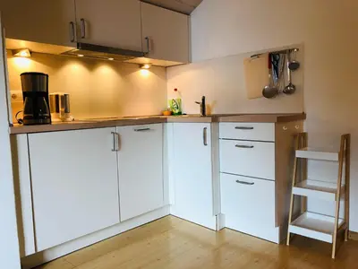 a kitchen with white cabinets and a wooden floor at Matailerhof in Tirolo
