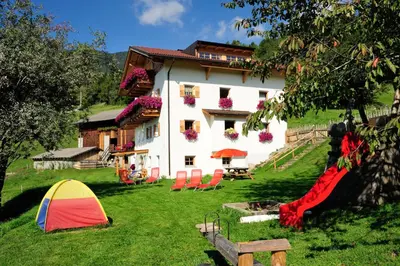 a house with a tent and chairs in the yard at Steierhof in Feldthurns