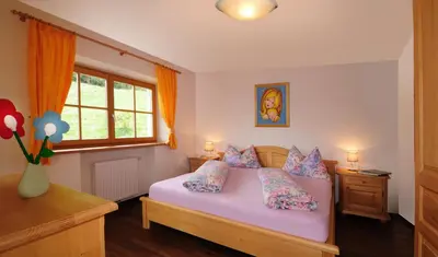 a bedroom with a pink bed with pillows and a window at Steierhof in Feldthurns