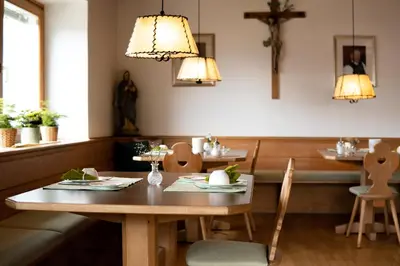 a dining room with a table and a cross on the wall at Active B&B Prairerhof in Schenna
