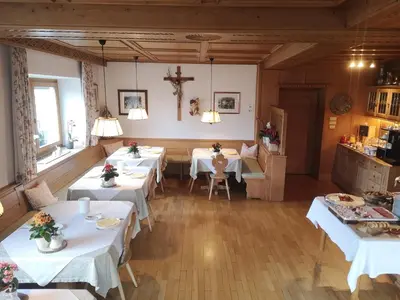 a dining room with white tables and a cross on the wall at Active B&B Prairerhof in Schenna