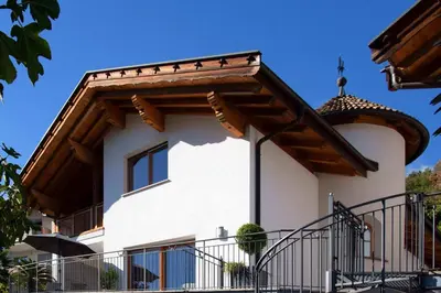 a white building with a wooden roof at Residence Untermösslhof in Lana