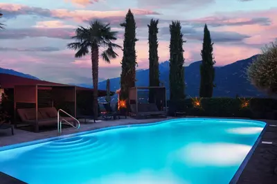 a swimming pool in a resort with palm trees at Residence Untermösslhof in Lana