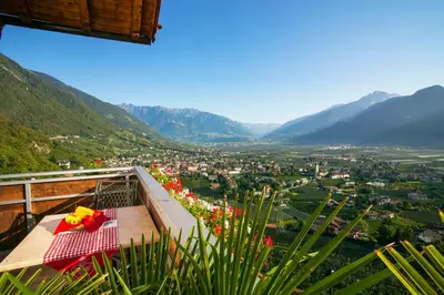 a table on a balcony with a view of a valley at Residence Untermösslhof in Lana