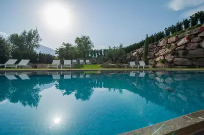 a swimming pool with chairs and a rock wall at Hidalgo Suites in Postal