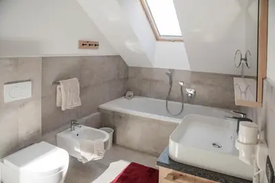 a bathroom with a sink and a toilet and a bath tub at Penthouse Chalet Pichlerhof in Brunico