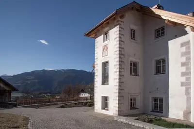 a white building with mountains in the background at Penthouse Chalet Pichlerhof in Brunico