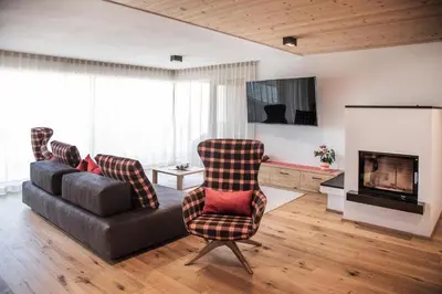 a living room with a couch and chairs and a television at Penthouse Chalet Pichlerhof in Brunico