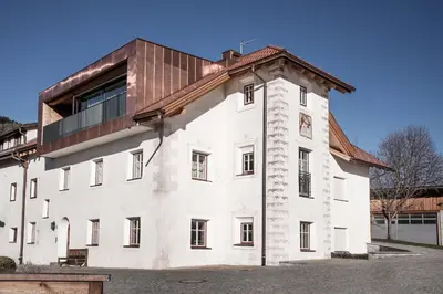 a white building with a brown roof at Penthouse Chalet Pichlerhof in Brunico