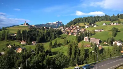 a town on a hill with green hills and trees at Vista Pelmo in Colle Santa Lucia