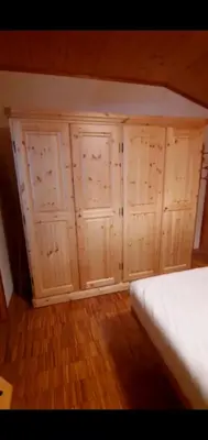 a bedroom with wooden cabinets and a white bed at Nuovo Appartamento Les Corceles in San Vigilio Di Marebbe