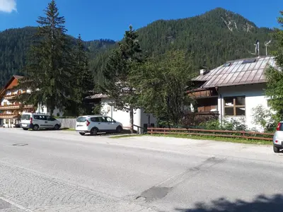 a street with cars parked in front of a building at Nuovo Appartamento Les Corceles in San Vigilio Di Marebbe