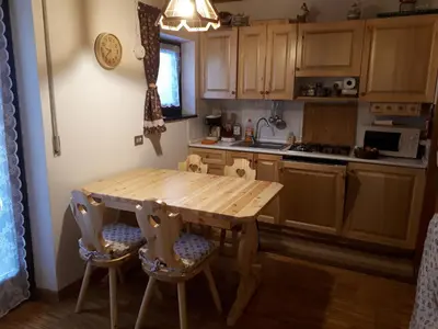 a kitchen with a wooden table and chairs at Nuovo Appartamento Les Corceles in San Vigilio Di Marebbe