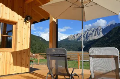two chairs and an umbrella on the porch of a cabin at Zyprianhof in Nova Levante