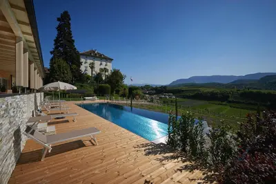 a swimming pool with chairs and a house at Weingut Windegg in Caldaro
