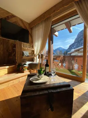 a living room with a table and a large window at Calore di una Casa di Montagna in Campitello di Fassa