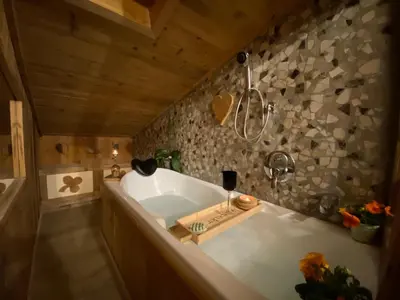 a large bath tub in a bathroom with a stone wall at Calore di una Casa di Montagna in Campitello di Fassa