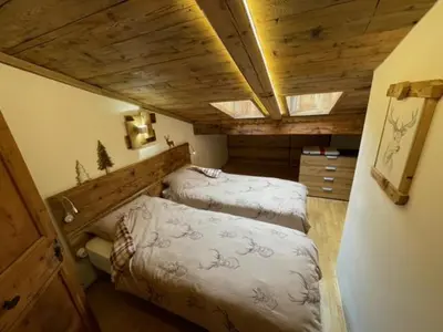 a bedroom with two beds in a room with wooden ceilings at Calore di una Casa di Montagna in Campitello di Fassa