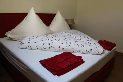 a bed with white sheets and red towels on it at Augustiner in Meran in Merano