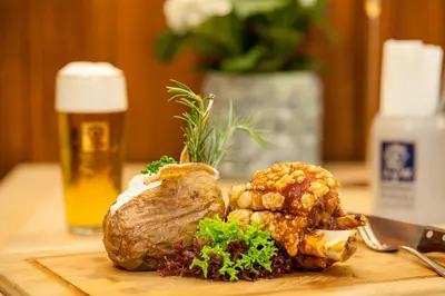 a steak on a cutting board with a glass of beer at Augustiner in Meran in Merano