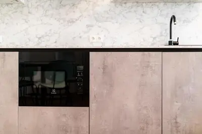 a kitchen with a counter with a sink and a chair at Stay COOPER l Cooper apartments in Bolzano