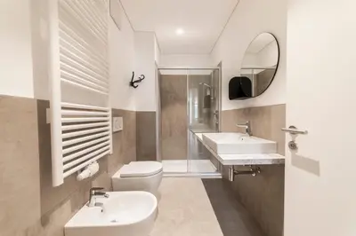 a bathroom with a toilet and a sink and a mirror at Stay COOPER l Cooper apartments in Bolzano