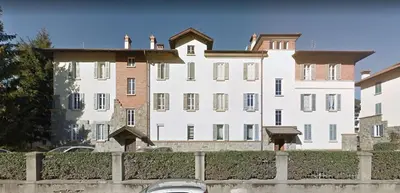 a large white building with a fence in front of it at Plose Apartment in Bressanone