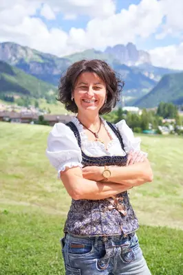 a woman standing in a field with her arms crossed at Eco-Green Fiores Agriturismo in Vigo di Fassa