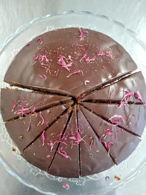 a chocolate cake with pink sprinkles on a glass plate at Eco-Green Fiores Agriturismo in Vigo di Fassa
