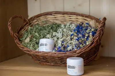 a basket filled with flowers on a table with two medicines at Eco-Green Fiores Agriturismo in Vigo di Fassa
