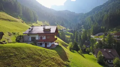 a house on a hill in a green valley at Chalet Prinoth in Selva di Val Gardena