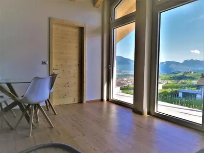a room with a table and chairs and large windows at Orizzonti d'Anaunia in Tassullo