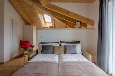 a bedroom with a large bed in a room with wooden ceilings at Orizzonti d'Anaunia in Tassullo