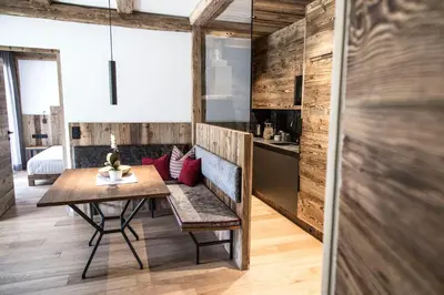 a dining room with a table and a room with a bed at Chalet Zenit in Selva di Val Gardena