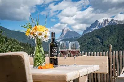 a table with two glasses of wine and a vase of flowers at ban Hofa in Bressanone