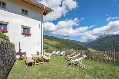 a patio with chairs and a table and a fence at ban Hofa in Bressanone