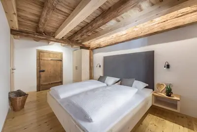 a large white bed in a room with a wooden ceiling at ban Hofa in Bressanone