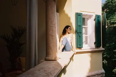 a woman sitting on the ledge of a window at Villa Arnica, a Member of Design Hotels in Lana