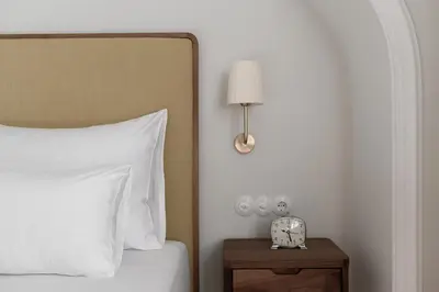 a bedroom with a bed and a nightstand with a clock at Villa Arnica, a Member of Design Hotels in Lana