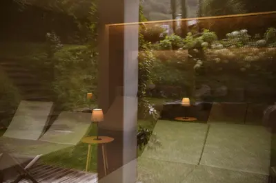 a view of a garden from a window with two lamps at Villa Arnica, a Member of Design Hotels in Lana