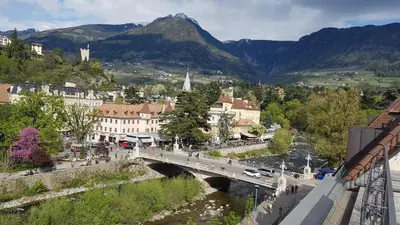 a bridge over a river in a town with mountains at Appartamento centro terme merano in Merano