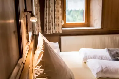 a bedroom with two beds and a light and a window at Oberwirt in Selva dei Molini