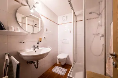 a white bathroom with a sink and a shower at Oberwirt in Selva dei Molini