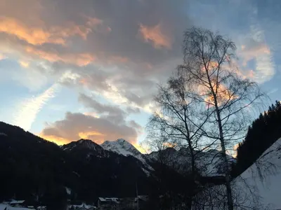 a sunset in the mountains with a tree in the foreground at Oberwirt in Selva dei Molini